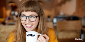 Smiling Young Female with Glasses Holding Mug After Tooth Extraction